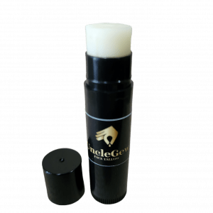 Tube of UncleGew Lip Balm with creamy texture, surrounded by ingredients like beef tallow, jojoba seeds, beeswax, and vanilla bean, showcasing its all-natural, organic formulation for nourished, protected lips.