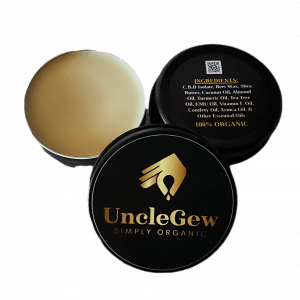 A portable tin of UncleGew Salve filled with creamy, rich salve, surrounded by botanical ingredients such as calendula flowers, arnica, almond kernels, and jojoba seeds. The natural, earthy aesthetic highlights its grass-fed beef tallow base and all-natural formulation, perfect for soothing dry skin and minor aches.